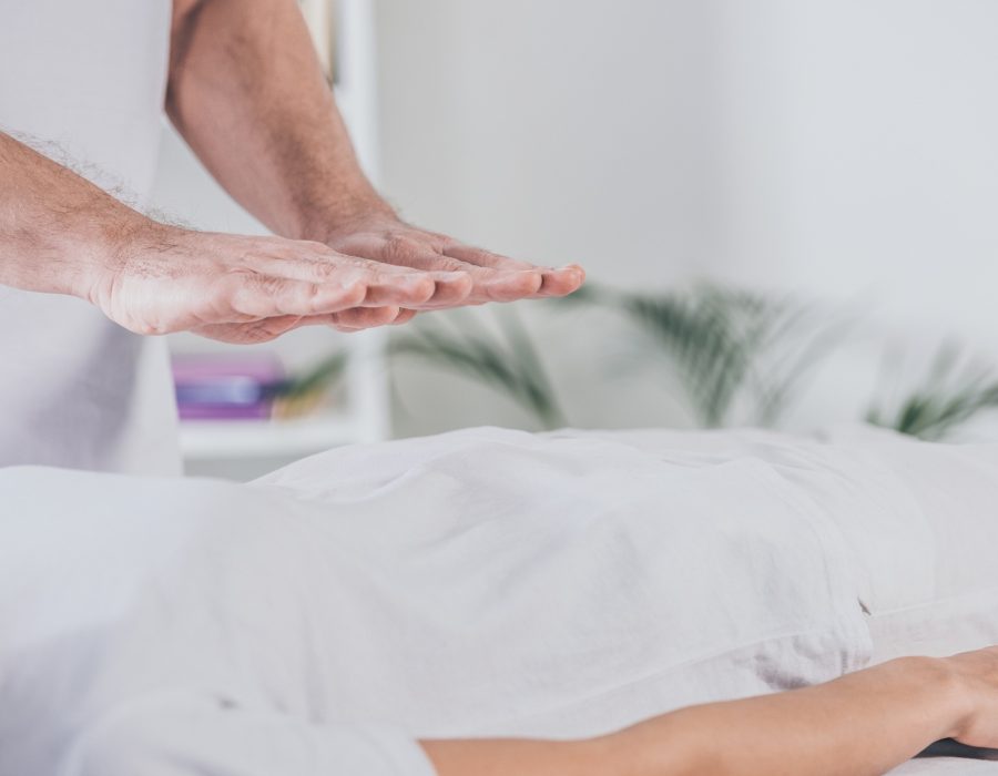cropped shot of male therapist doing reiki healing session to woman